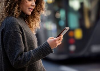 Mulher jovem usando smartphone para acessar serviços do GOV.BR