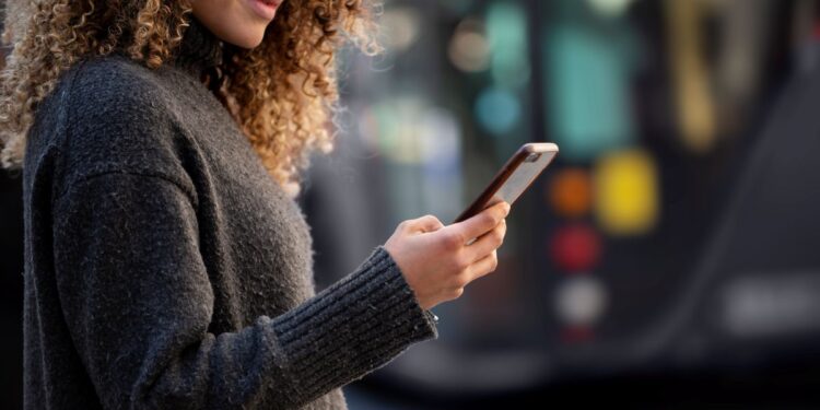 Mulher jovem usando smartphone para acessar serviços do GOV.BR
