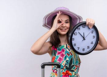 Mulher jovem com chapéu segurando relógio, simbolizando contagem regressiva para o próximo feriado prolongado de 2025.