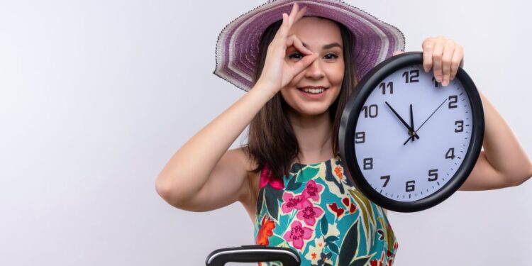 Mulher jovem com chapéu segurando relógio, simbolizando contagem regressiva para o próximo feriado prolongado de 2025.