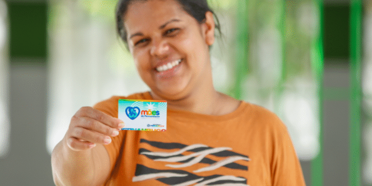Mulher segurando cartão do Programa Mães de Pernambuco.