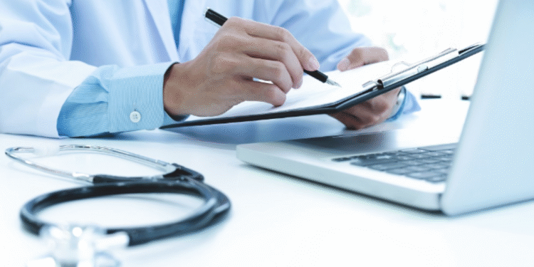 Médico analisando documentos e usando computador, com planos de saúde atendendo pacientes do SUS.