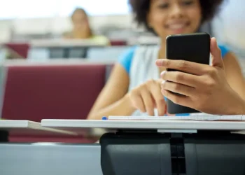 Estudante usando o celular em sala de aula, simbolizando o acesso à internet gratuito.