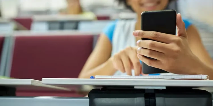 Estudante usando o celular em sala de aula, simbolizando o acesso à internet gratuito.
