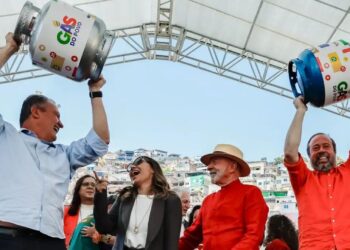 Representantes do governo comemoram o lançamento do programa Gás do Povo com botijões simbólicos erguidos.