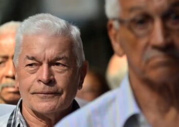 homem idoso com cabelos brancos, em foco, caminhando em grupo de pessoas mais velhas