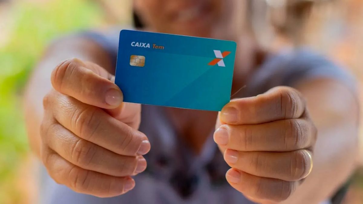 Pessoa segurando cartão de crédito CAIXA Tem em destaque nas mãos.