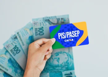Cartão do PIS/PASEP da Caixa Econômica Federal sobre notas de R$ 100, simbolizando o saque dos valores.