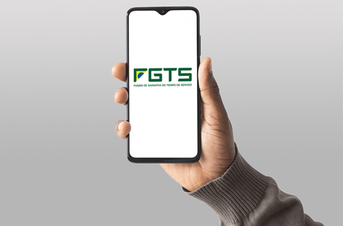 Mão segurando celular com logo do FGTS na tela branca.