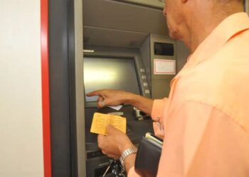 Pessoa utilizando um caixa eletrônico para consultar o extrato, simbolizando a necessidade de acompanhar as movimentações financeiras.