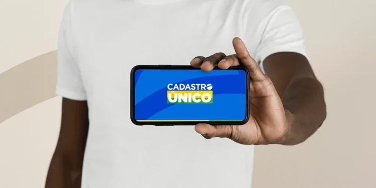Pessoa segura um celular exibindo o aplicativo do Cadastro Único em tela azul.