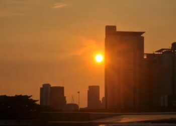 Pôr do sol sobre uma cidade moderna, destacando-se em um cenário urbano.