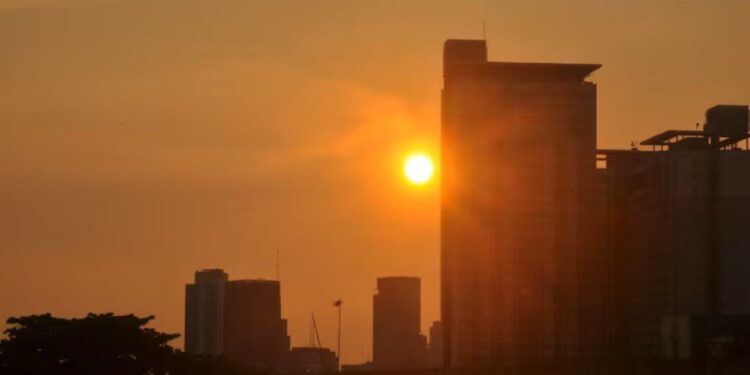 Pôr do sol sobre uma cidade moderna, destacando-se em um cenário urbano.