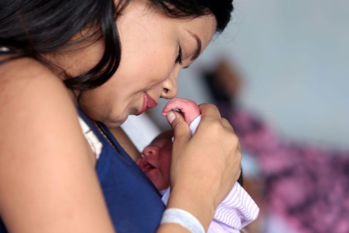 Mãe abraça recém-nascido com carinho em ambiente hospitalar