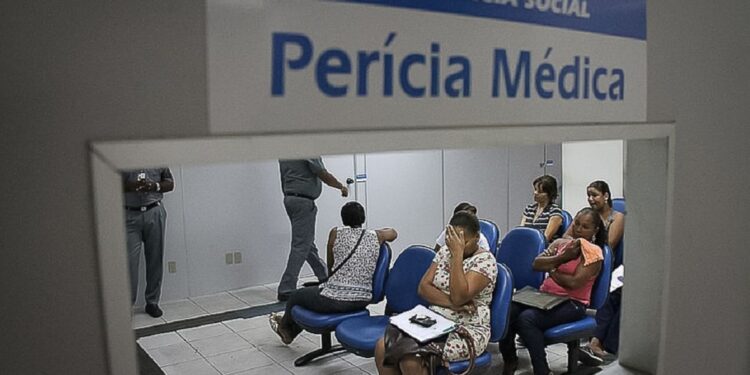 Pessoas aguardam atendimento na sala de espera da perícia médica do INSS.