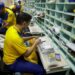 Funcionário dos Correios do Brasil manuseando e separando pacotes em uma bancada com caixas de correio ao fundo.