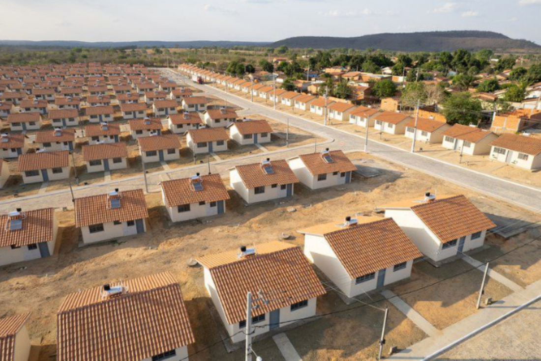 Conjunto habitacional do programa Minha Casa Minha Vida com diversas casas uniformes e ruas pavimentadas.