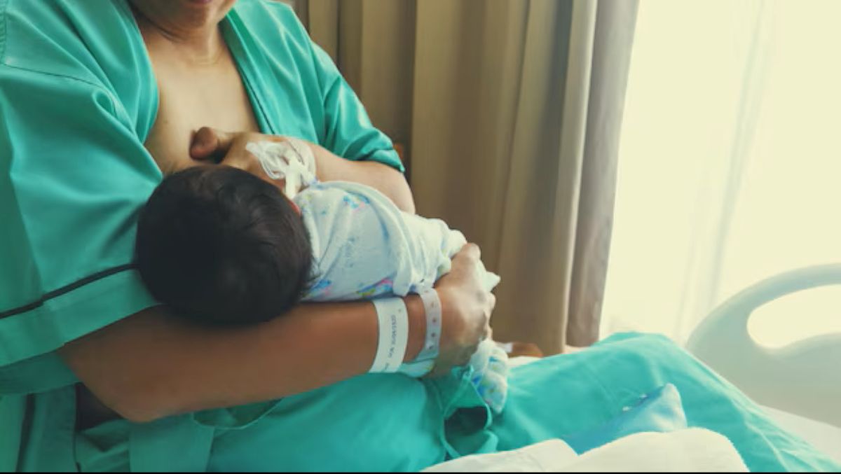 Mãe amamentando recém-nascido na cama do hospital, representando a ampliação da licença-maternidade.
