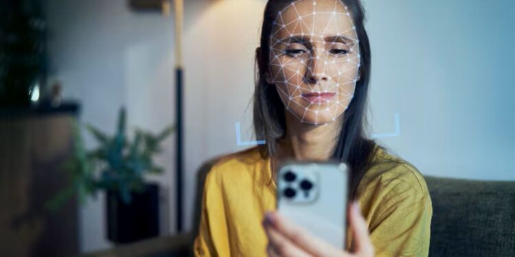 Mulher jovem tem o rosto escaneado por um smartphone, ilustrando o uso do reconhecimento facial para autenticação.