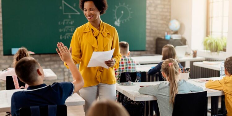 Professora negra sorridente interagindo com alunos em sala de aula, simbolizando a carreira docente e as regras de aposentadoria