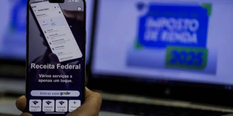 Tela do app Receita Federal com opções de serviços e computador ao fundo