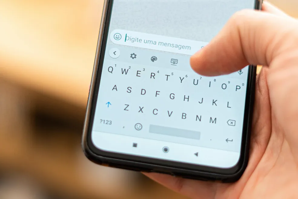 Pessoa digitando uma mensagem no celular, ilustrando o uso de WhatsApp para fraudes como o golpe da compra retida.