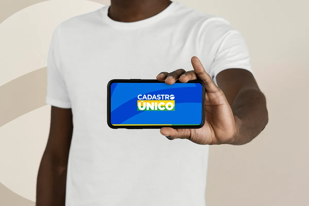 Homem segurando um smartphone que exibe o logotipo do Cadastro Único em tela, representando o acesso digital a informações e atualizações do sistema.
