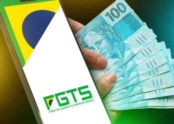 Tela de celular exibindo logo do FGTS e mão segurando cédulas de 100 reais brasileiras