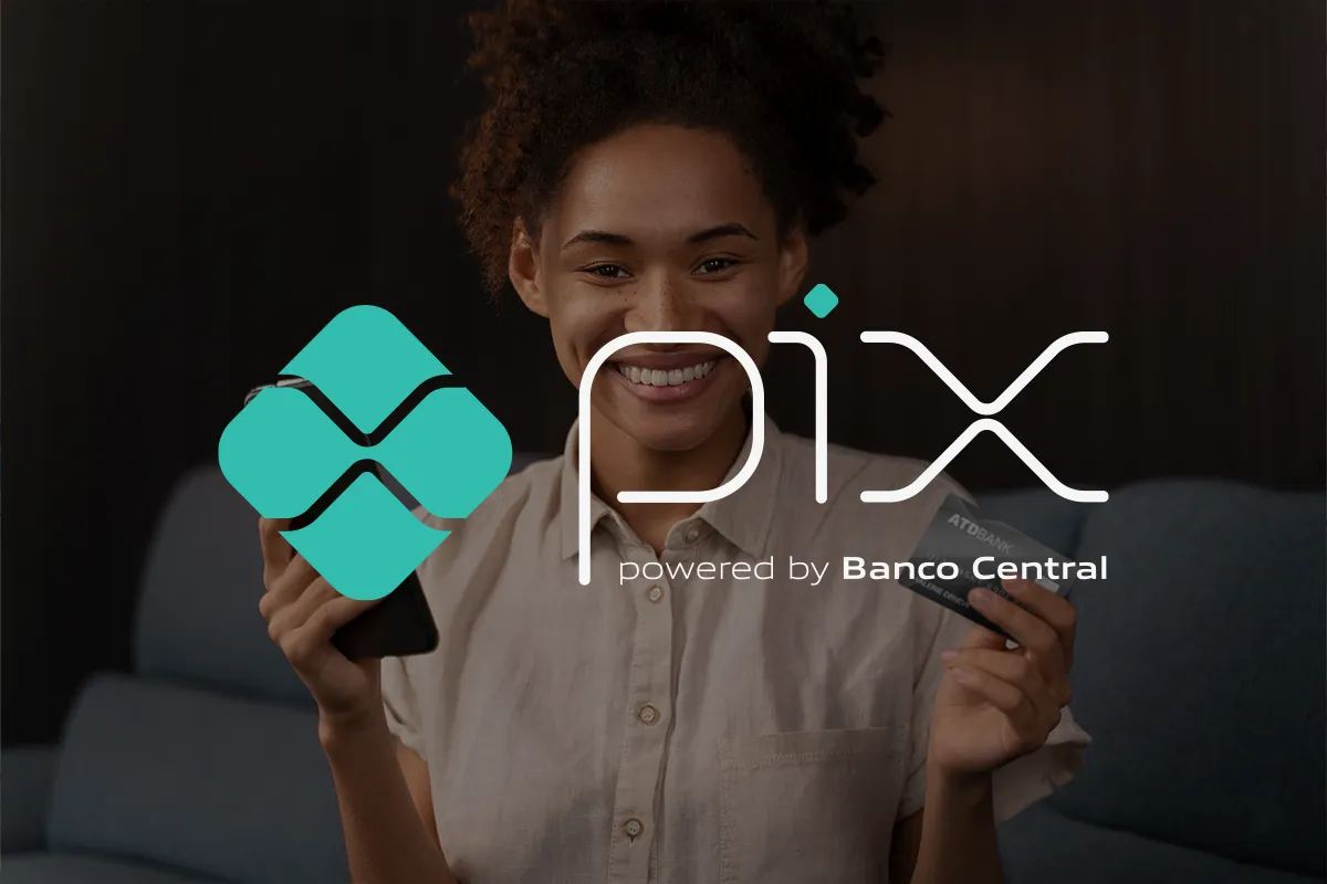 Pessoa sorrindo e segurando celular e cartão de banco, ilustrando a adoção do Pix Automático.