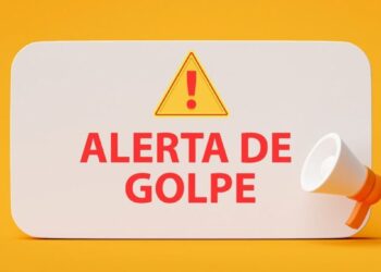 Placa branca com os dizeres 'ALERTA DE GOLPE' em vermelho e um ícone de exclamação, acompanhada de um megafone, sobre um fundo amarelo.