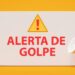 Placa branca com os dizeres 'ALERTA DE GOLPE' em vermelho e um ícone de exclamação, acompanhada de um megafone, sobre um fundo amarelo.