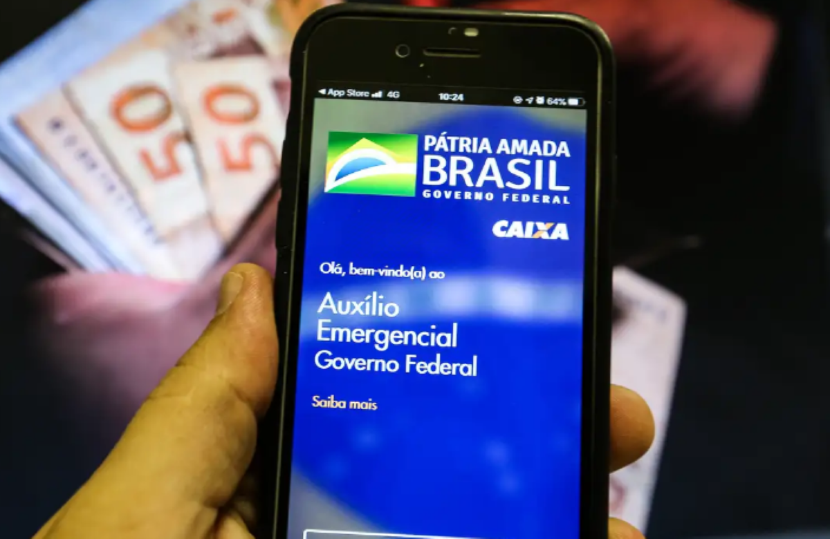 Pessoa segura celular com o aplicativo do Auxílio Emergencial do Governo Federal aberto na tela.