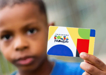 Criança segurando o cartão do programa Bolsa Família.