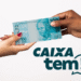Duas mãos trocando uma nota de 100 reais com o logo Caixa Tem ao lado.