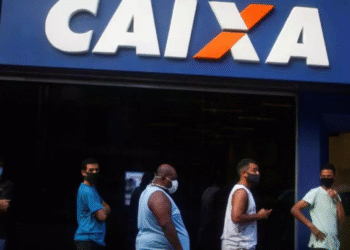 Pessoas em fila em frente a uma agência da Caixa Econômica Federal.
