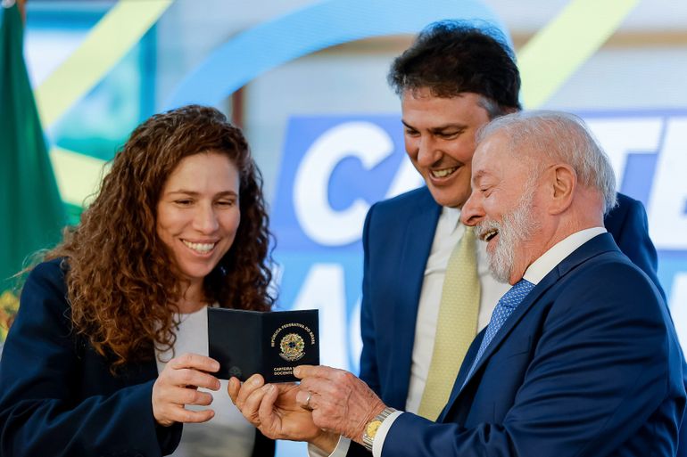 Professora segurando carteira docente profissional em cerimônia oficial