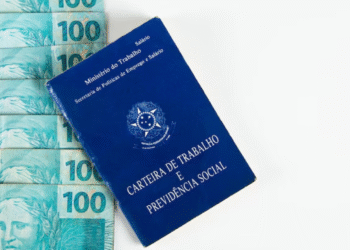 Carteira de Trabalho sobre notas de 100 reais, simbolizando benefícios trabalhistas.