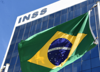 Fachada do prédio do INSS com bandeira do Brasil ao vento.