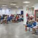 Pessoas em uma sala de espera, sentadas em cadeiras azuis, aguardando atendimento durante um mutirão extraordinário do INSS.