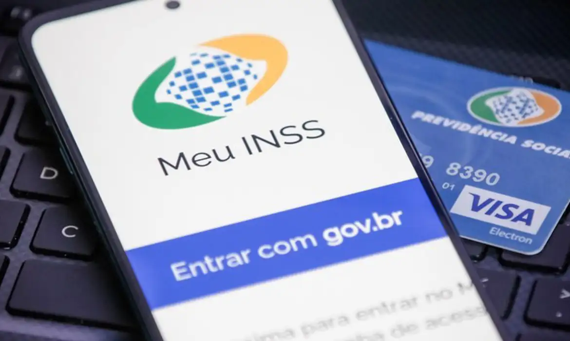 Tela de smartphone mostrando o aplicativo Meu INSS com botão Entrar com gov.br ao lado de cartão da Previdência Social
