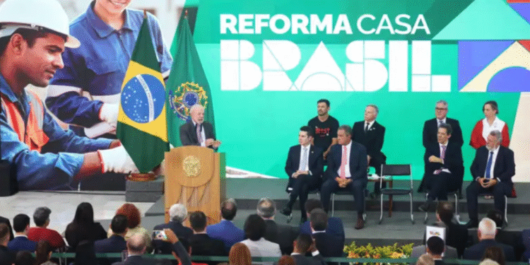 Presidente Lula em evento do programa Reforma Casa Brasil, com imagem de trabalhadores da construção civil ao fundo, simbolizando a execução das obras e o benefício direto à população.