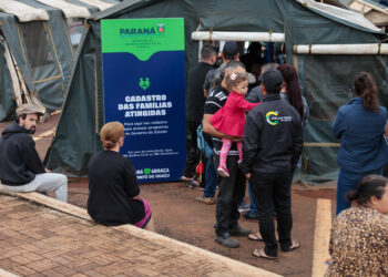 Pessoas em área de assistência/cadastro para auxílio emergencial com placa do Governo do Paraná (Programa Superação) em Rio Bonito do Iguaçu após tornado devastador.