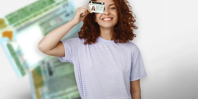 Jovem mulher com camiseta listrada segurando carteira de identidade na frente do rosto sorrindo