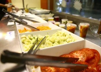 Bandejas com saladas frescas de tomate, couve-flor e cenoura em buffet de restaurante.