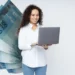 Mulher sorrindo usando computador com notas de R$ 100 ao fundo, representando o saque da CAIXA de R$ 2.800