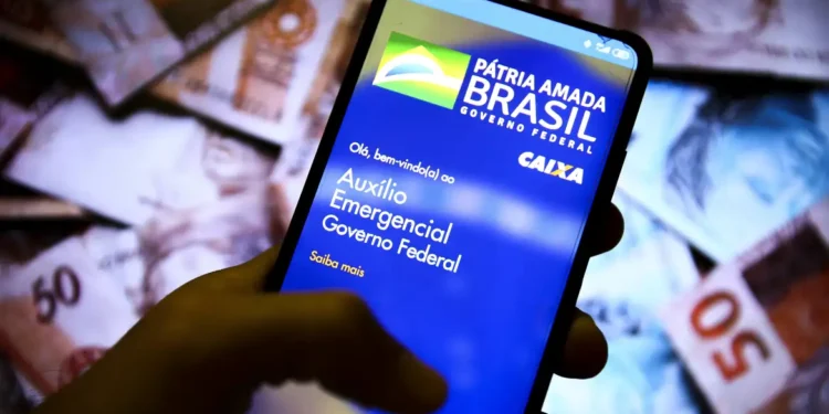 Smartphone exibindo app oficial do Auxílio Emergencial do Governo Federal em fundo de cédulas de reais