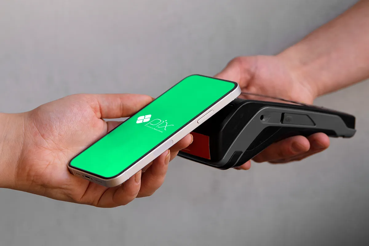 Pessoa realizando pagamento digital com celular usando Pix em máquina de cartão preta