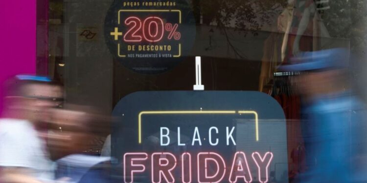 Fachada de loja com cartaz de promoção da Black Friday, simbolizando o consumo e os riscos de endividamento.