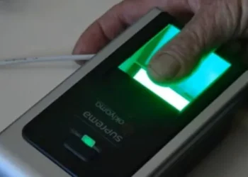 Mão segurando leitor biométrico com scanner de digital iluminado verde