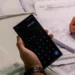Pessoa usando calculadora no celular e escrevendo valores em caderno para controlar contas e despesas
